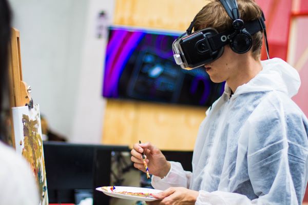 boy wearing vr-headset while painting on canvas